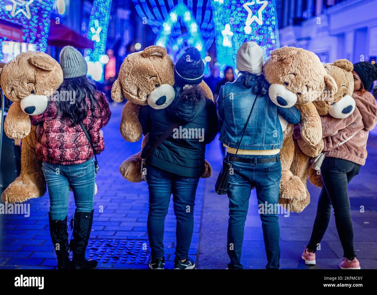 Tourists view the Christmas decorations in London's Mayfair and proudly hold on to their giant cuddly toys. Stock Photo