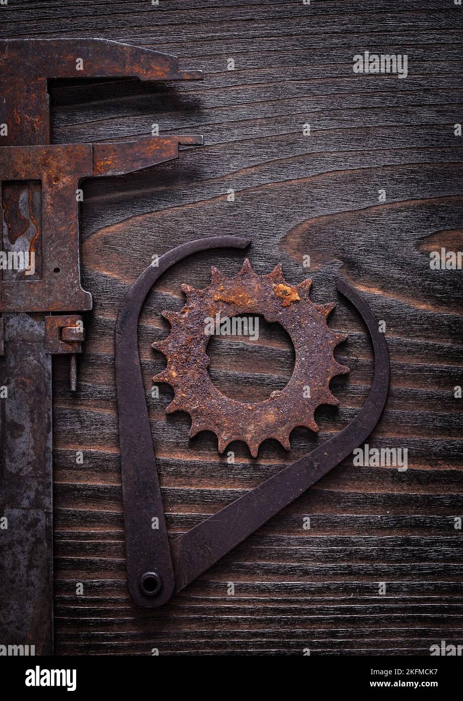 Rusted obsolete measuring calipers and gear wheel on vintage wooden