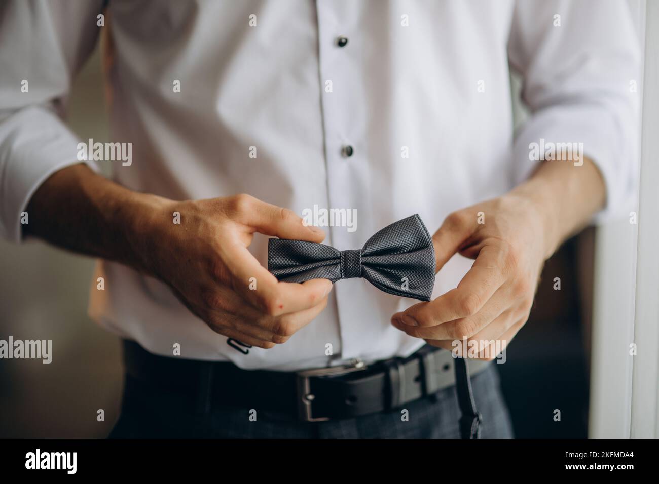 Close up portrait man ties a bowtie at the collar, on his white shirt