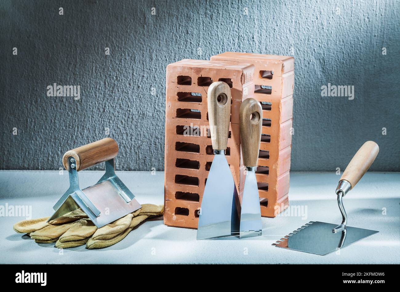 set of plastering trowels gloves and bricks on concrette background Stock Photo