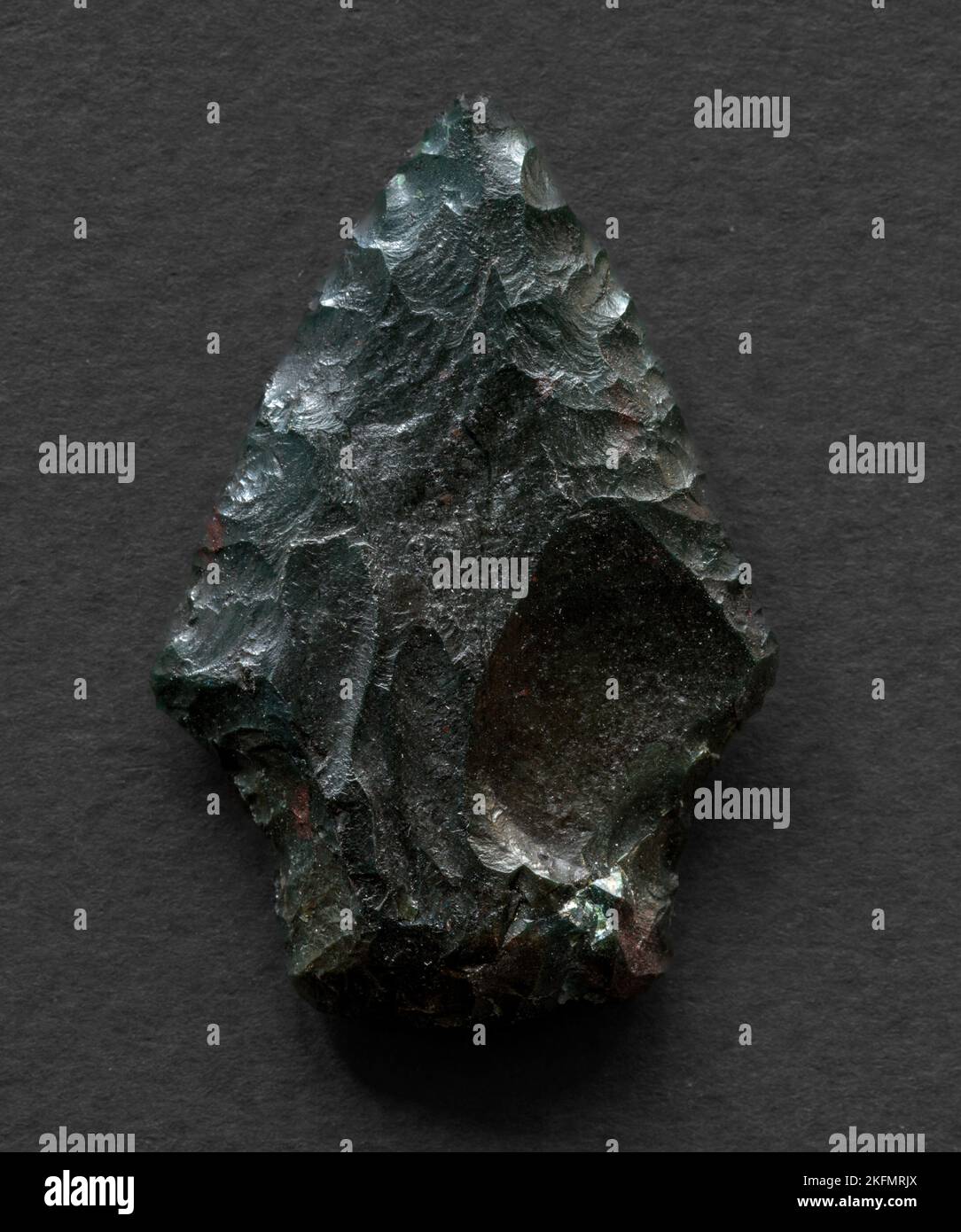 Neolithic obsidian arrowhead on dark background Stock Photo