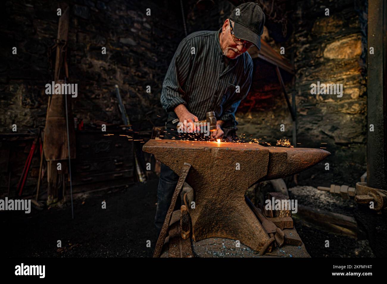 Sparks fly as a blacksmith forges steel on an anvil at the National Trust's Finch Foundry in Oakhampton, Devon to mark St Clement's Day, the patron saint for blacksmiths. Picture date: Saturday November 19, 2022. Stock Photo