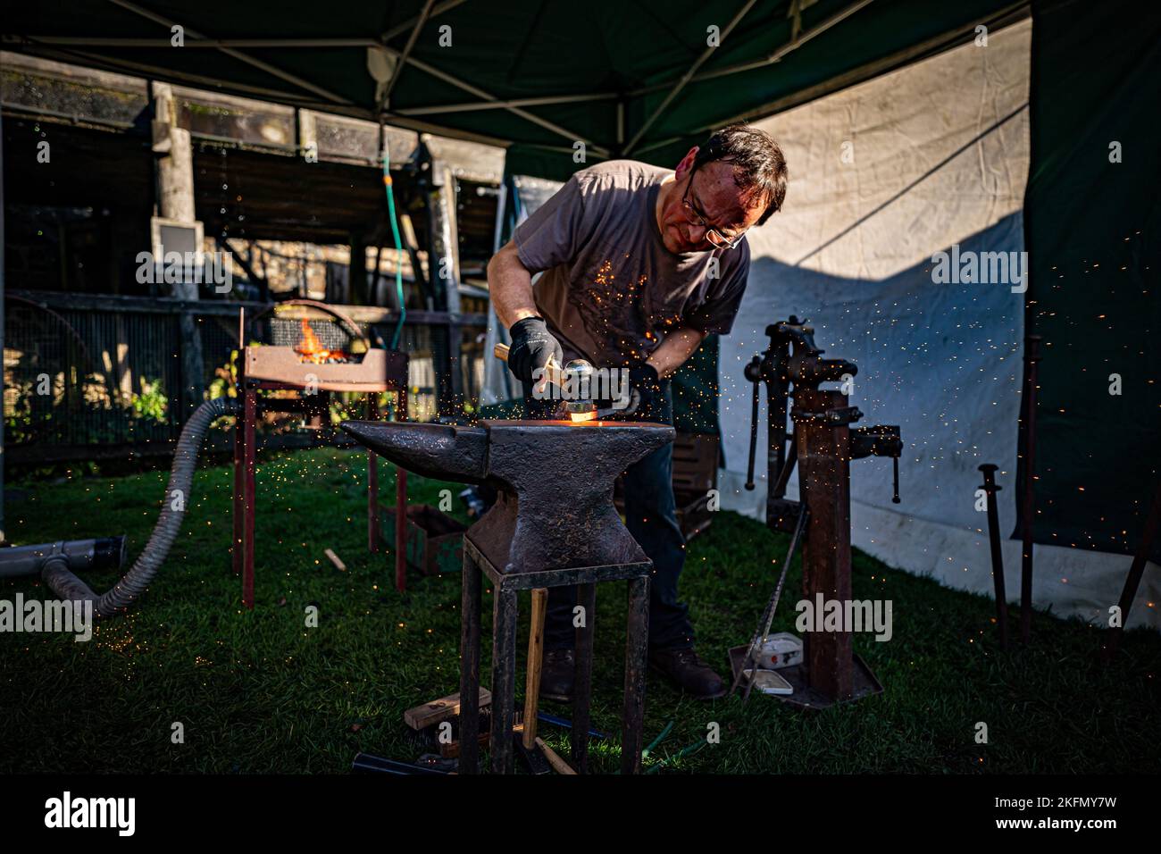 A blacksmith forges steel on an anvil at the National Trust's Finch Foundry in Oakhampton, Devon to mark St Clement's Day, the patron saint for blacksmiths. Picture date: Saturday November 19, 2022. Stock Photo
