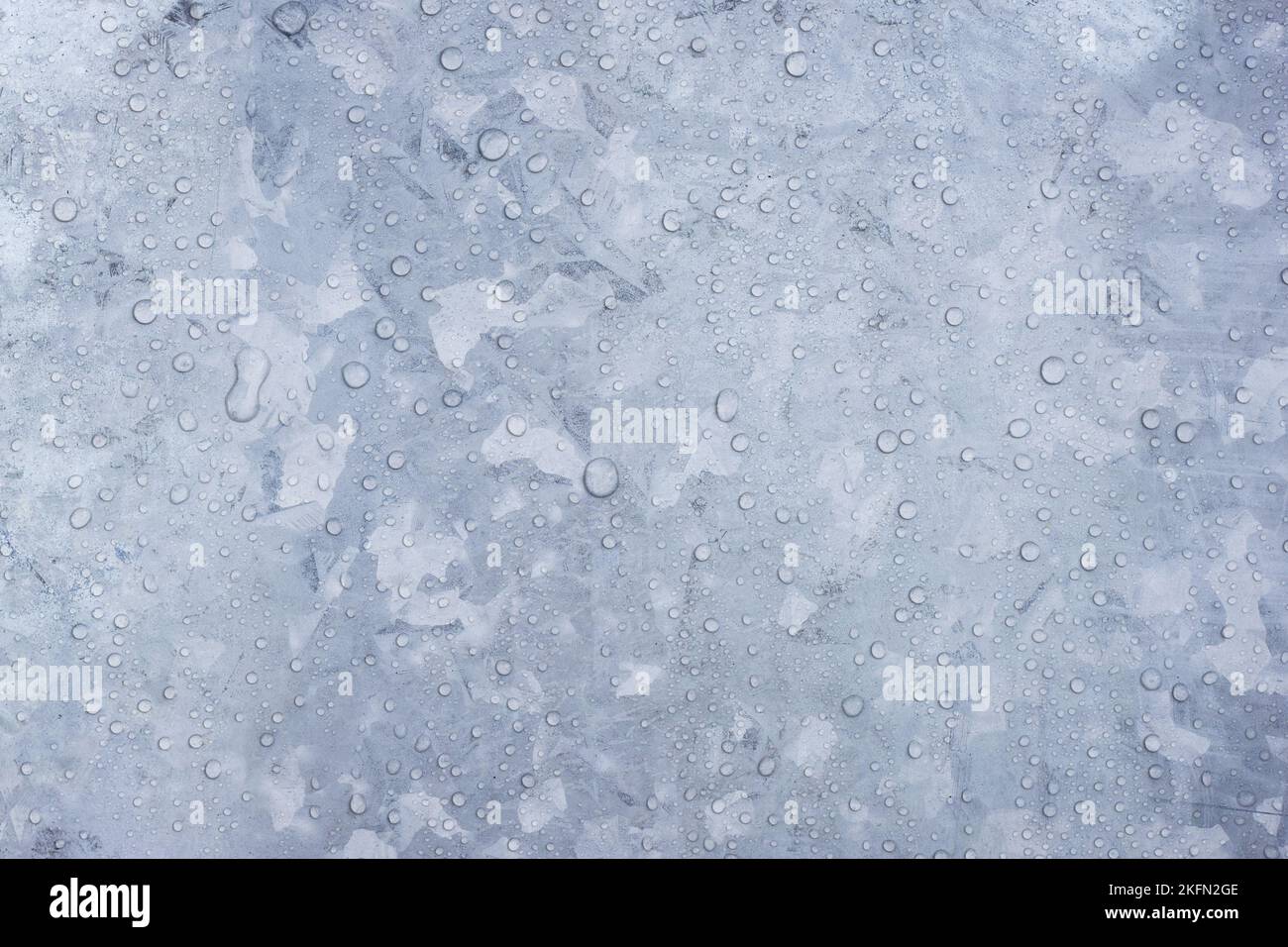 Closeup of water droplets on surface of galvanized gray zinc plate