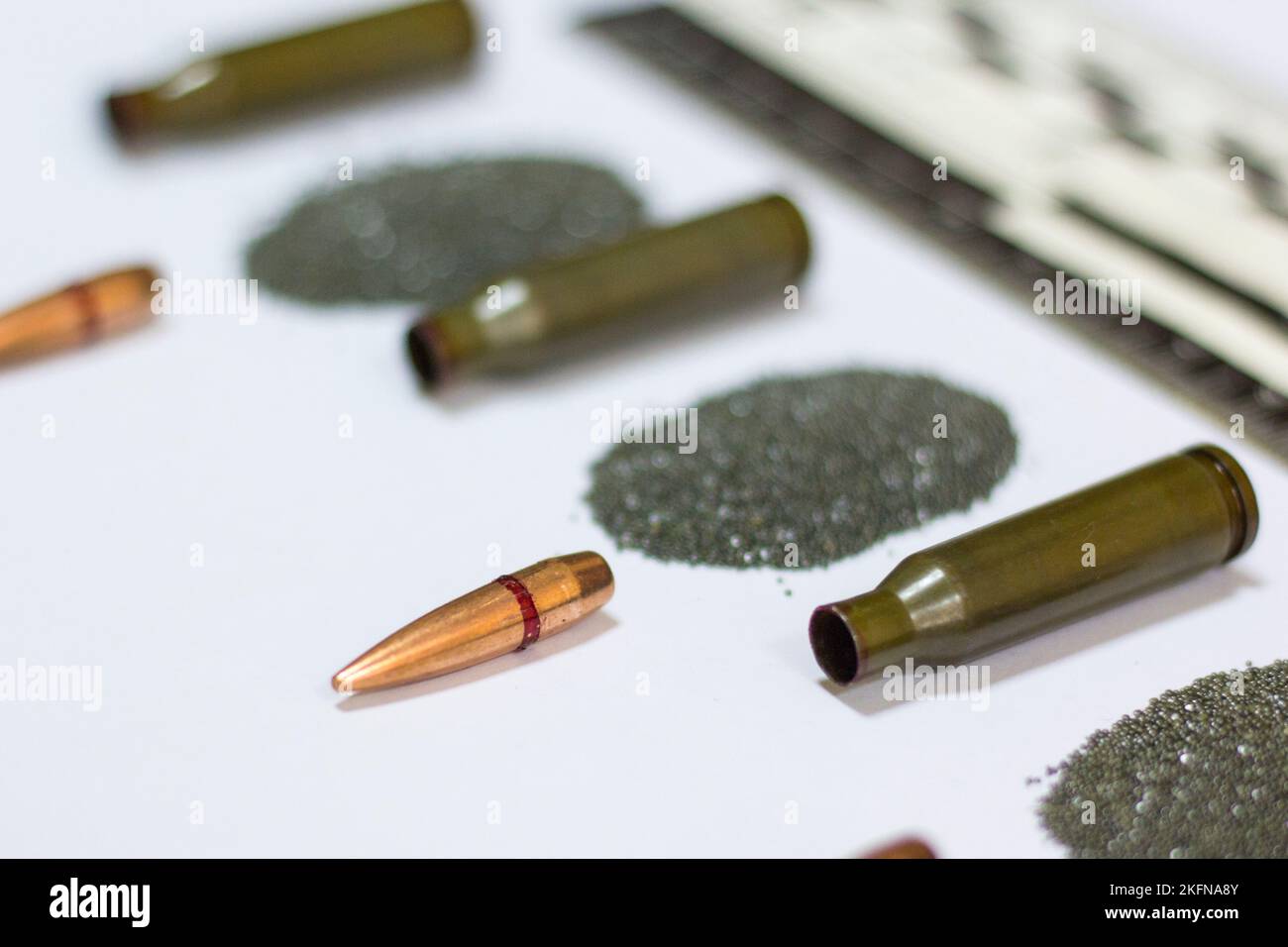 Bullet, cartridge case, cartridge, forensic ruler on a sheet of white