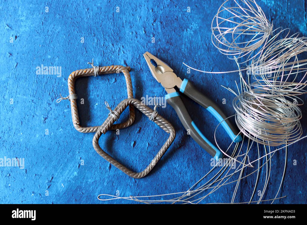 Vintage pliers, wire and reinforcement steel on blue textured background with copy space. House renovation work in details. Stock Photo