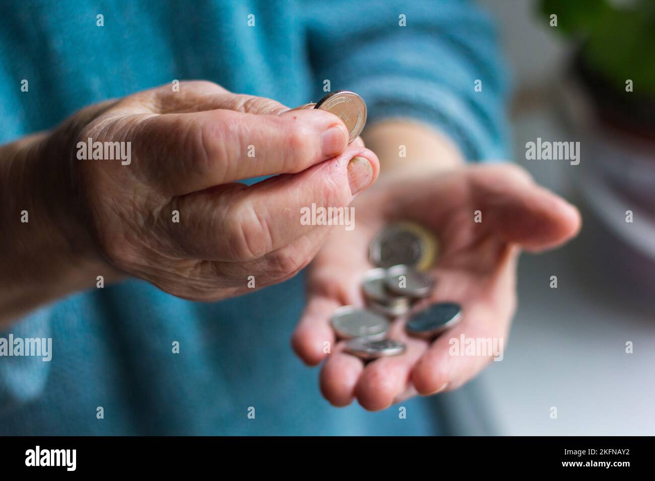 Grandma's wrinkled hands hold change in poverty Stock Photo