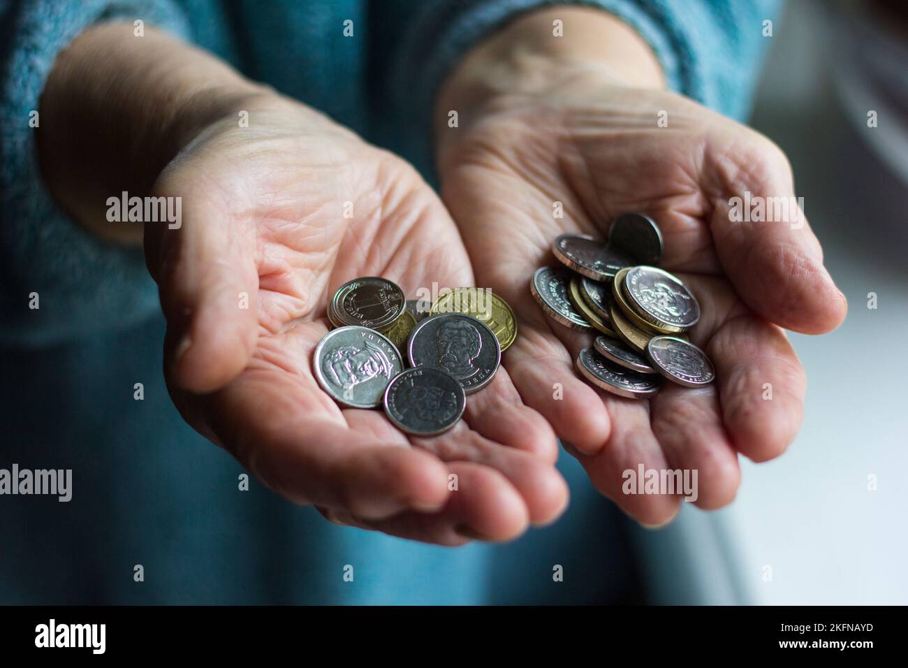 Grandma's wrinkled hands hold change in poverty Stock Photo