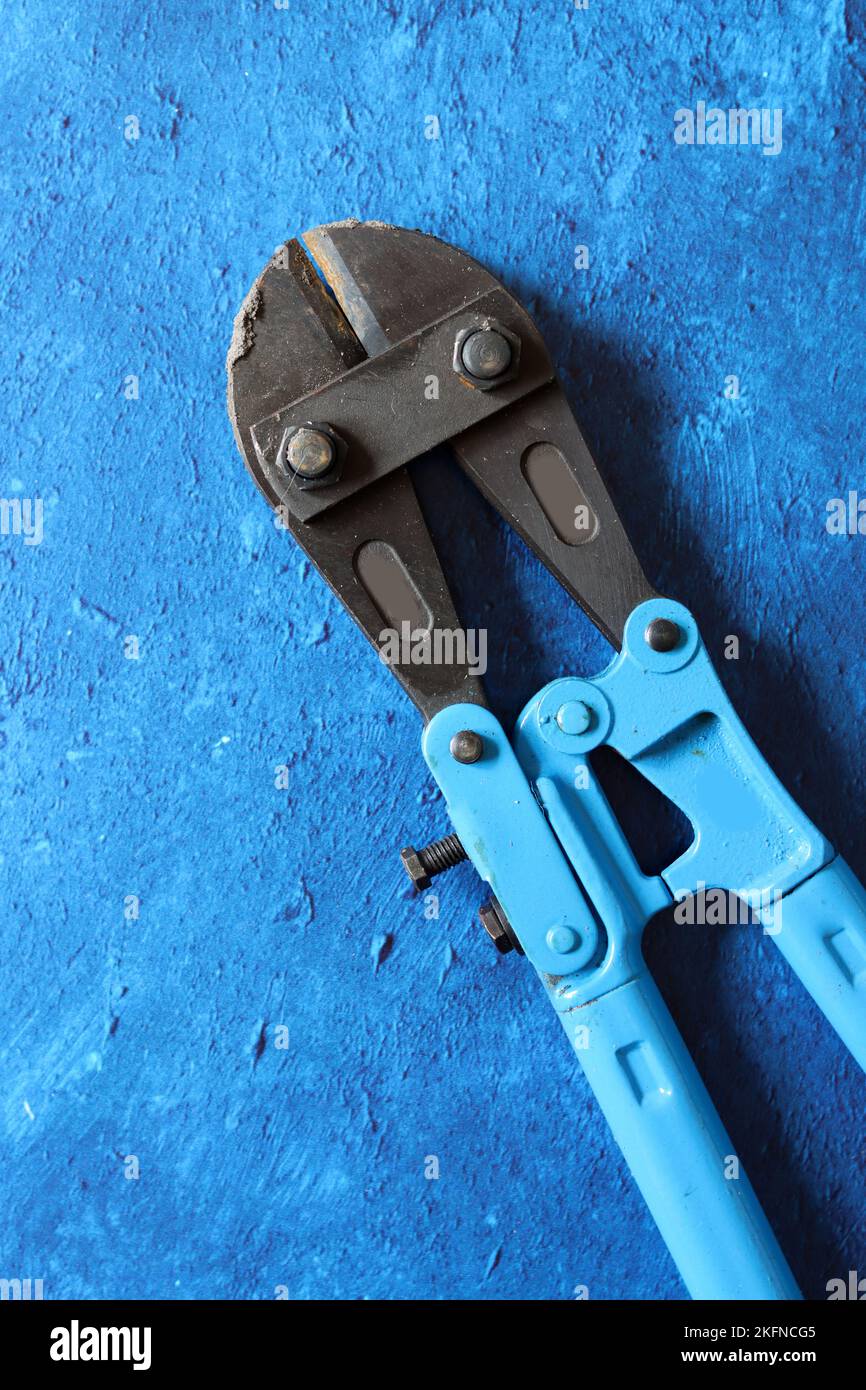 Tools on blue textured background with copy space. Vintage pliers close up photo. Handyman tools top view photo. Stock Photo