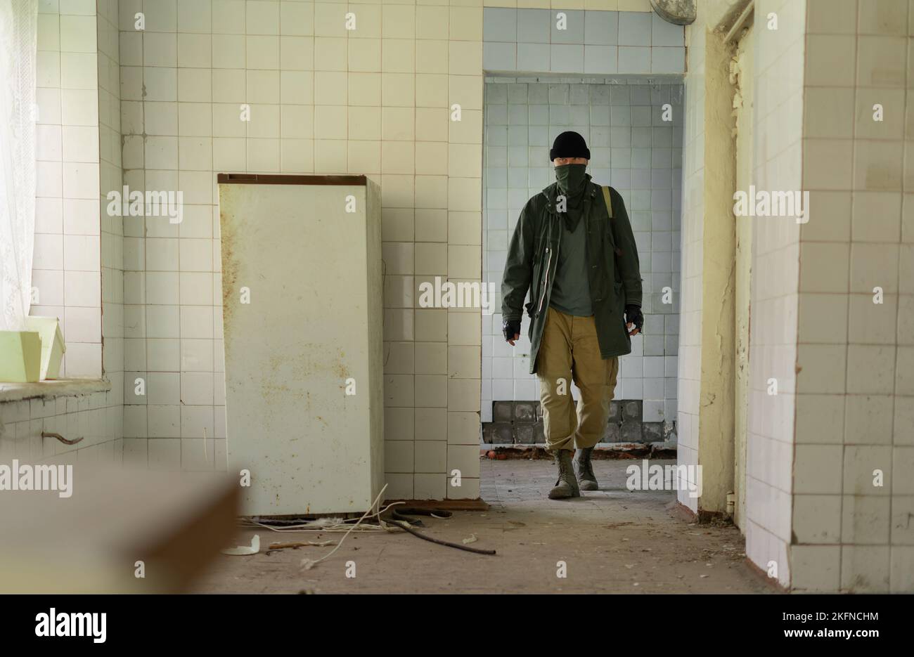 Post-apocalyptic survivor in a bandana, indoors ruins of a building, post-apocalyptic world, a man walking in search of food Stock Photo