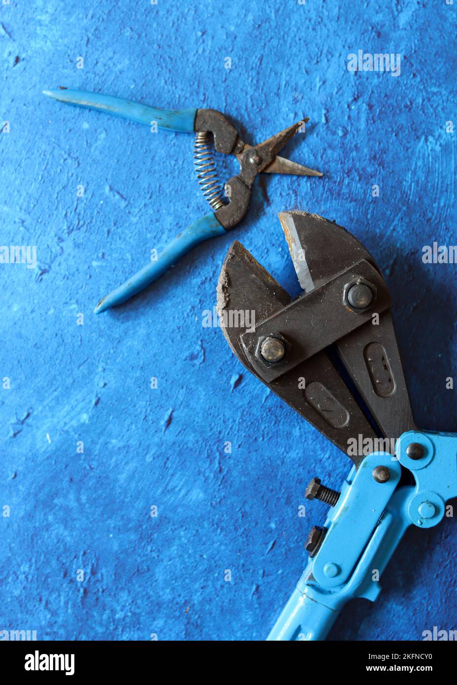 Tools on blue textured background with copy space. Vintage pliers close up photo. Handyman tools top view photo. Stock Photo