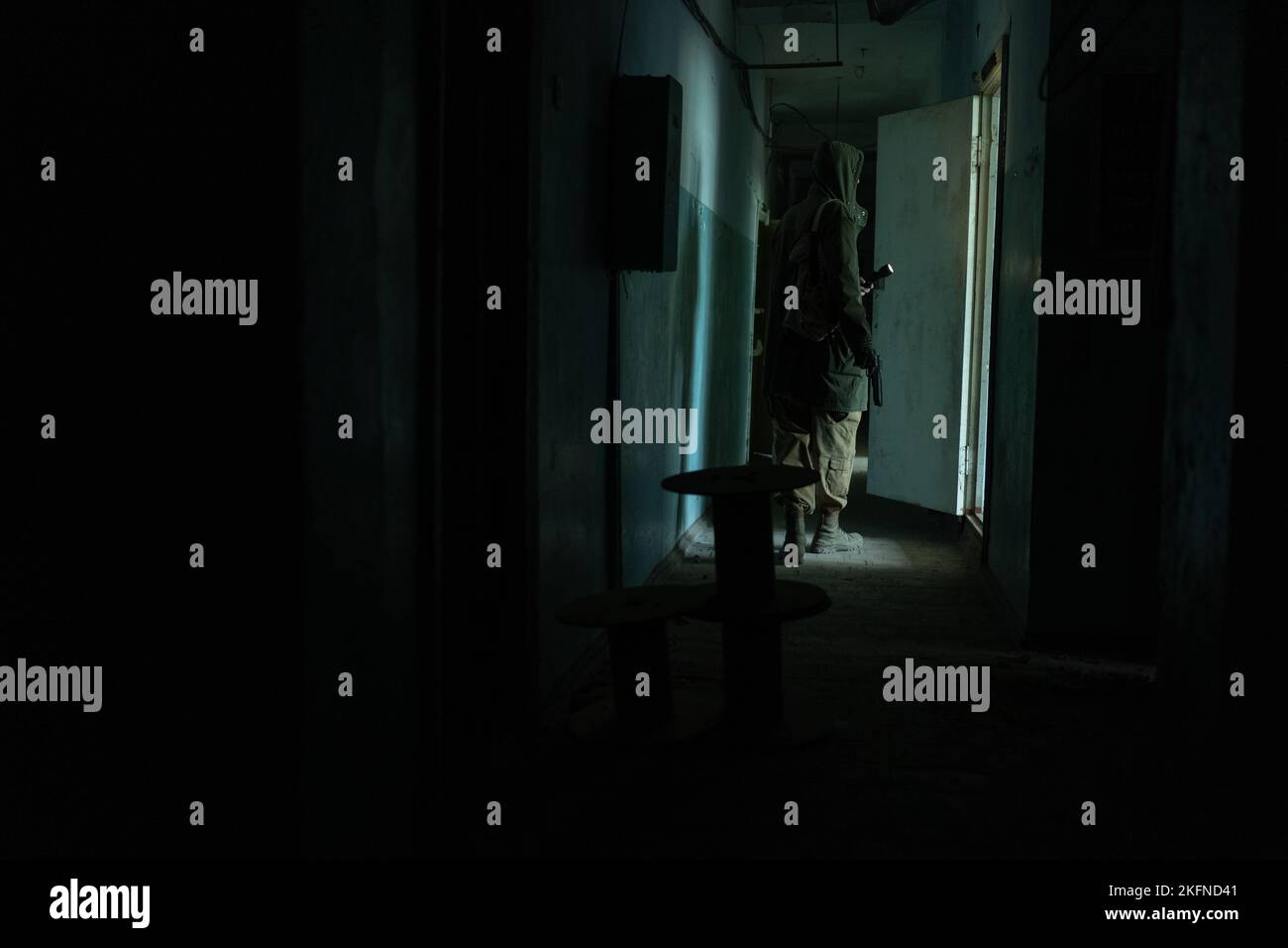 a man walking in a dark corridor of abandoned build, with flashlight in darkness Stock Photo