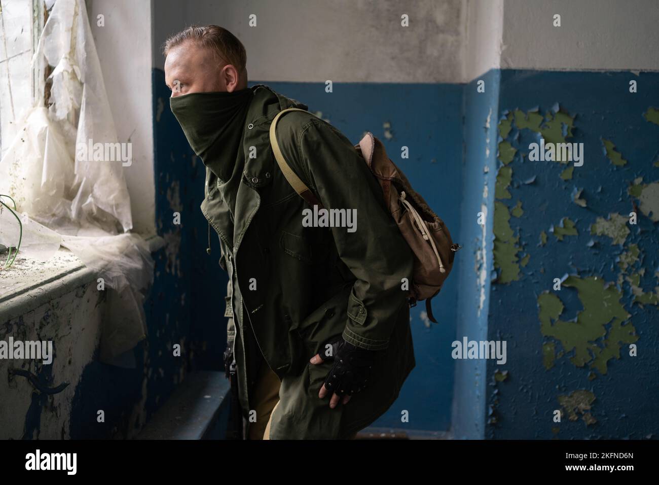 Man explorer with backpack and mask inside of abandoned industrial building, post apocalyptic survivor concept. Stock Photo