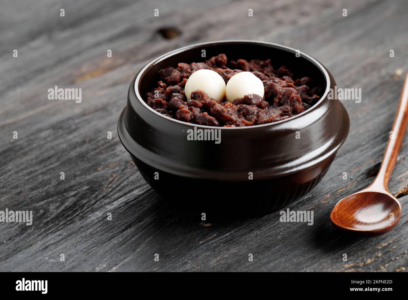 Patjuk, Korean Red Bean Porridge with Rice Cake on Top. Served on Black Wooden Table Stock Photo