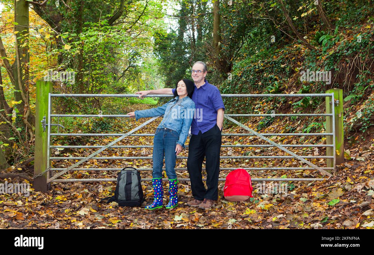 Couple resting against woodland gate in Autumn Stock Photo