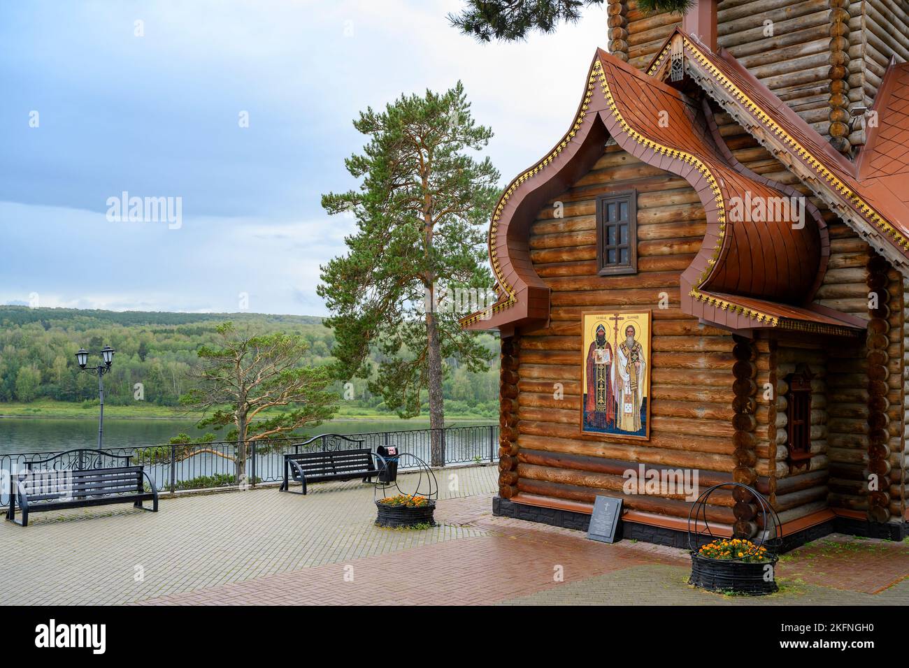 A fragment of a wooden Christian Orthodox Сhurch with the text of a prayer on a stone tablet near the Tom River in Siberia, Russia, under a rainy sky Stock Photo
