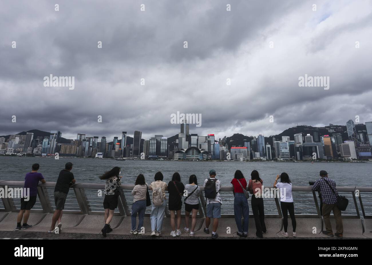 Members of the public watch the Government Flying Services helicopters carrying the national and SAR flags fly past and sea parade during the flag-raising ceremony at Golden Bauhinia Square in Wan Chai to celebrate the 25th anniversary of the establishment of the HKSAR, viewing from the Tsim Sha Tsui promenade, while police patrol and stand guard. 01JUL22 SCMP / Nora Tam Stock Photo