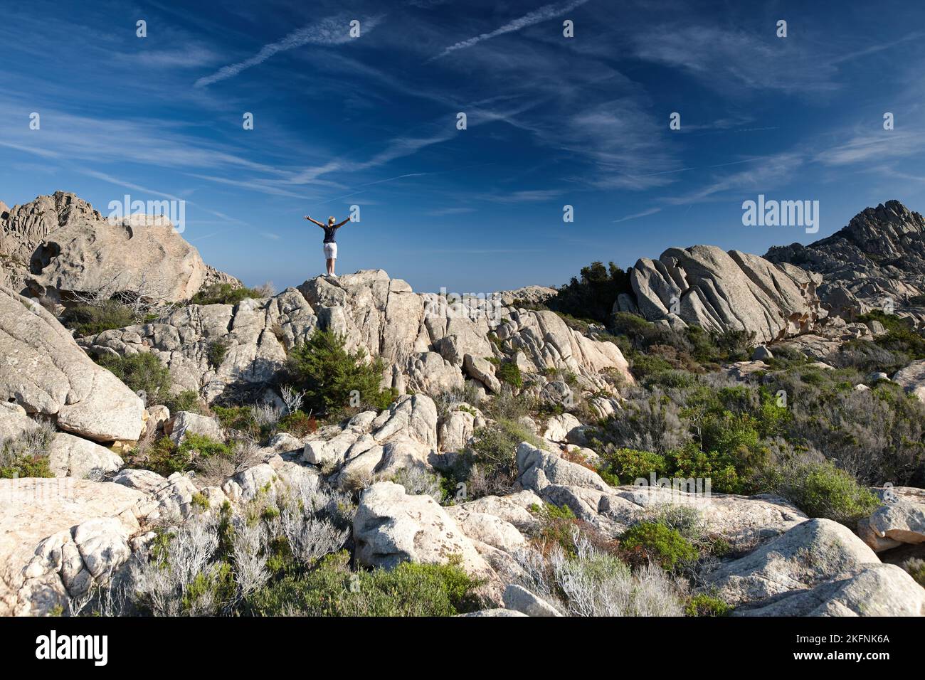 A single person walking on massive rough rocks under a blue sky Stock ...
