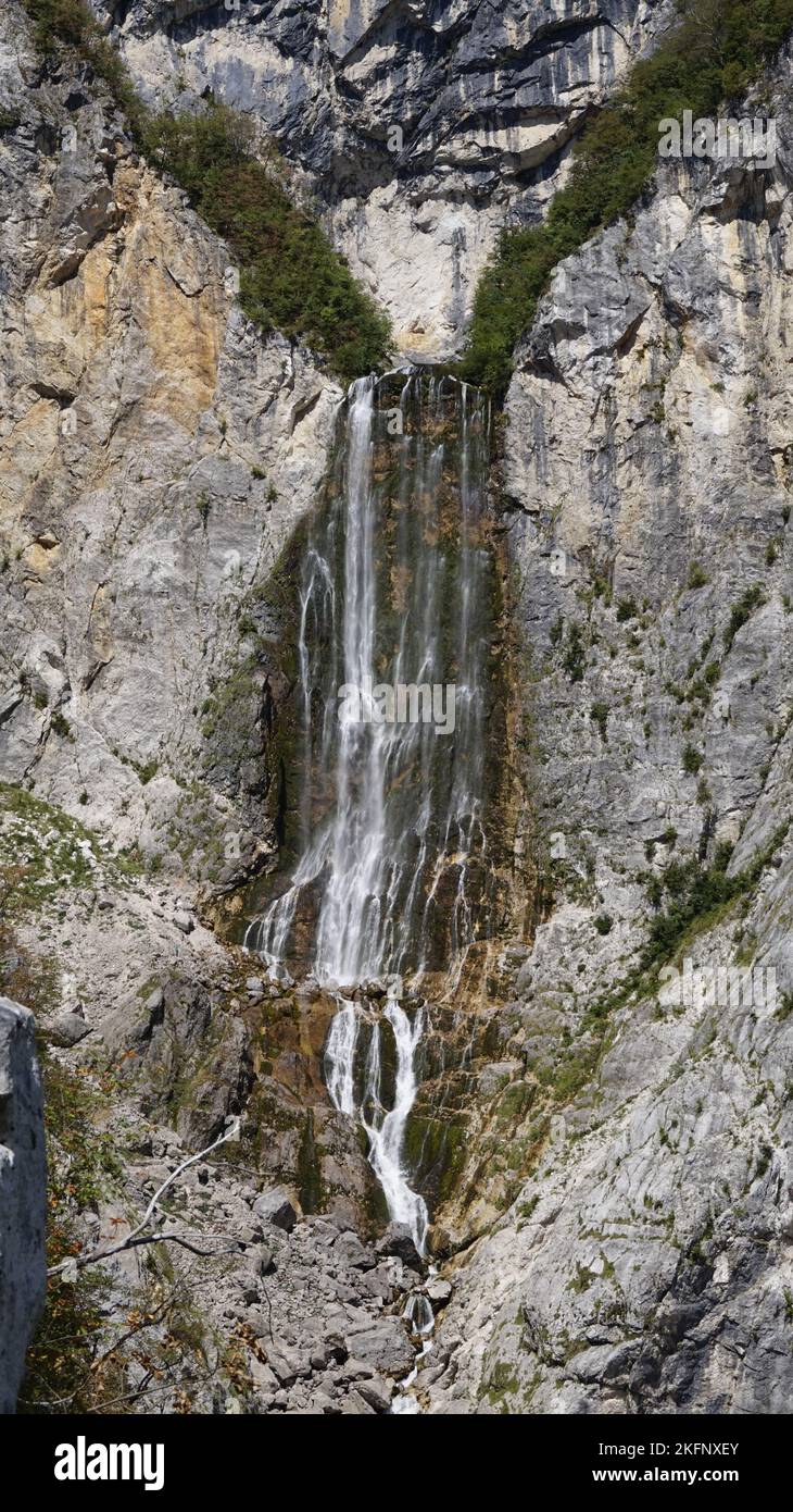 A vertical shot of a small waterfall flowing between the rocky ...