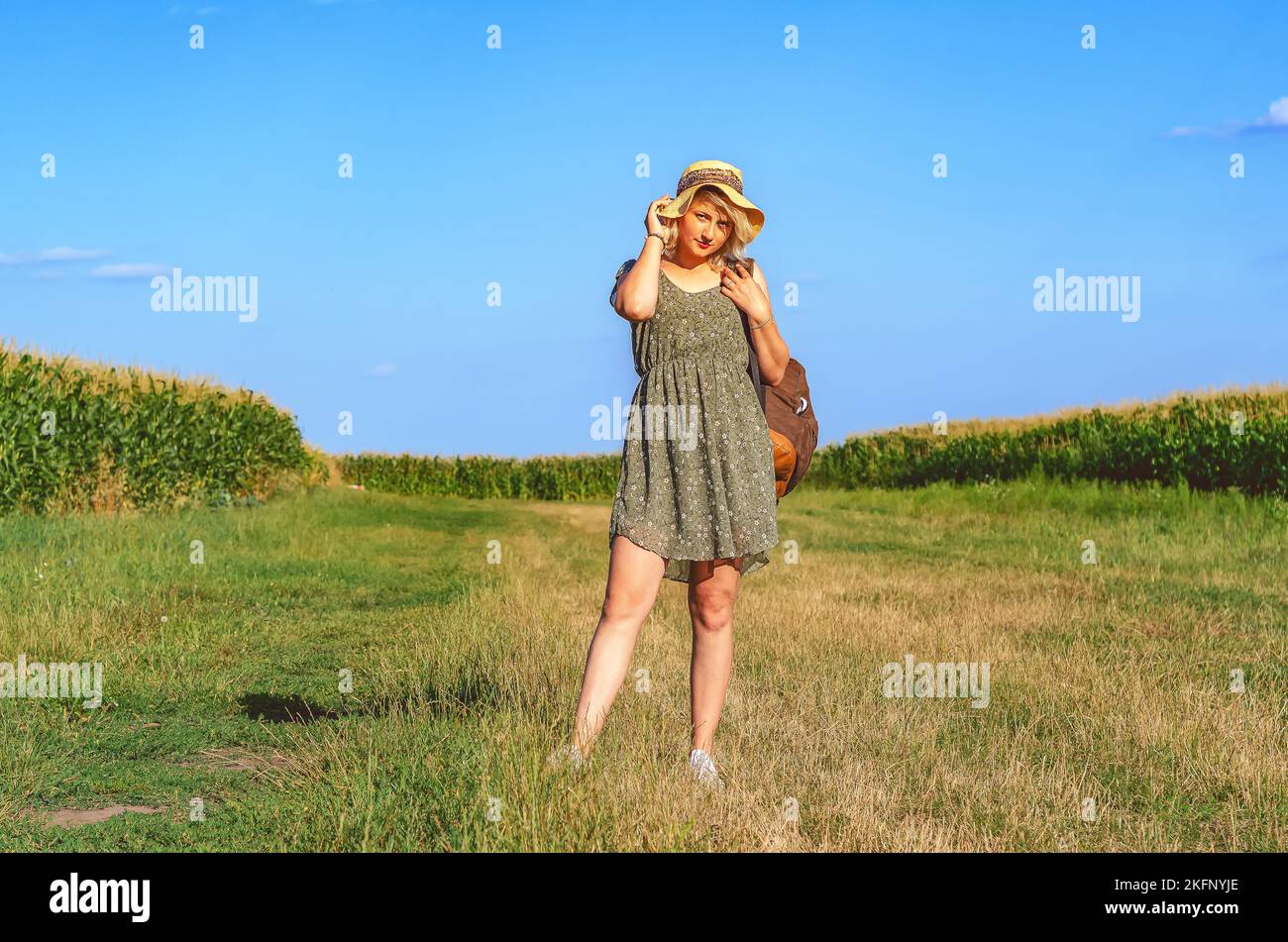 Gorgeous woman in a wheat field on a sunset background. A fashionable girl with long hair rejoices, laughs, enjoys life and summer, nature, happiness. Stock Photo