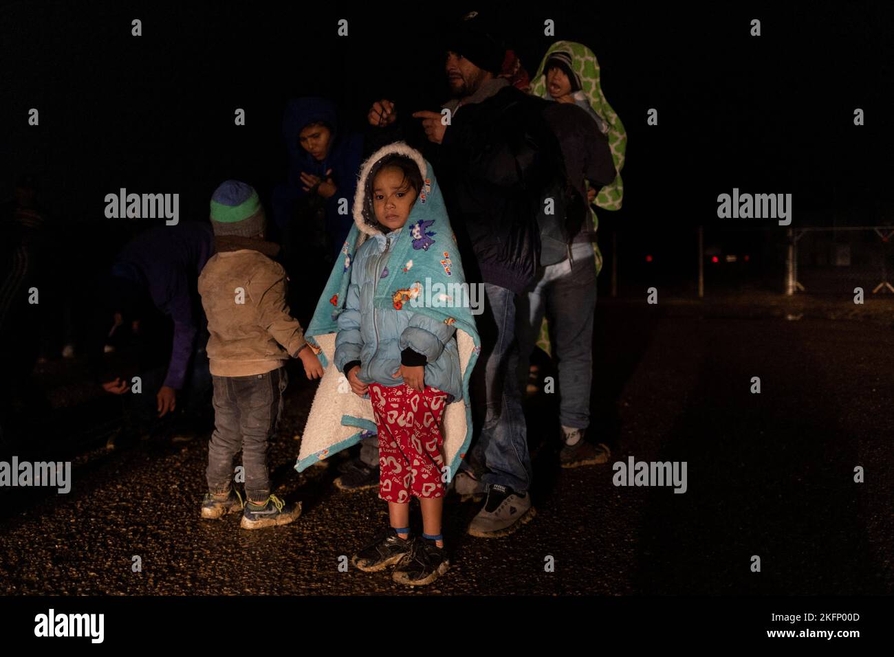 Karla, 5, of Honduras, stands near family members as they await to be registered by border patrol agents after being smuggled across the Rio Grande river from Mexico into Roma, Texas, U.S., November 18, 2022.  REUTERS/Adrees Latif Stock Photo