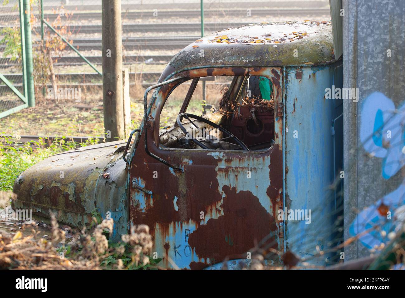 An abandoned truck rusts, the paint that was blue peels off and disappears. The interior of the cabin is rusty and damaged. Stock Photo