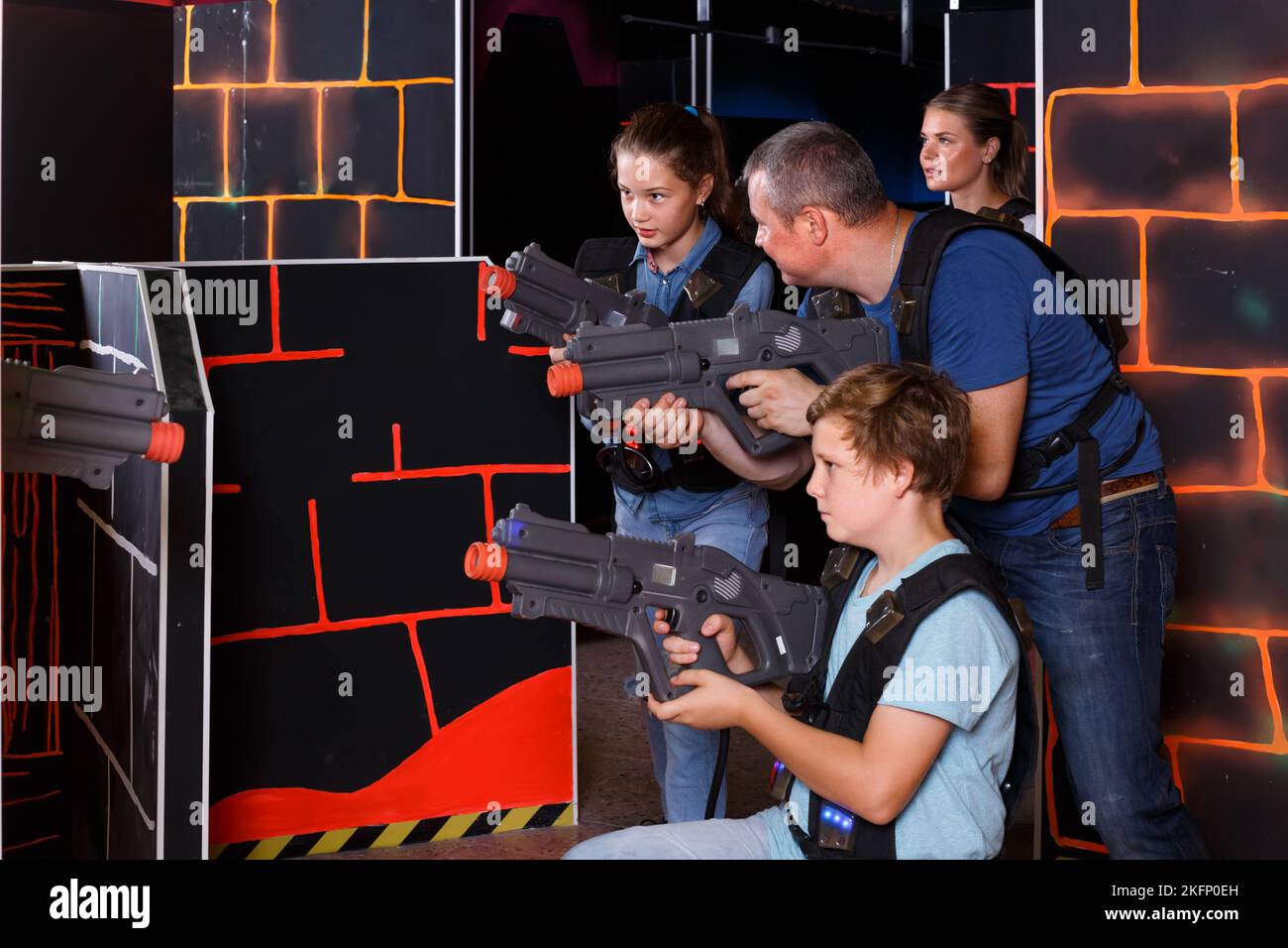 positive young parents and children with laser pistols playing laser
