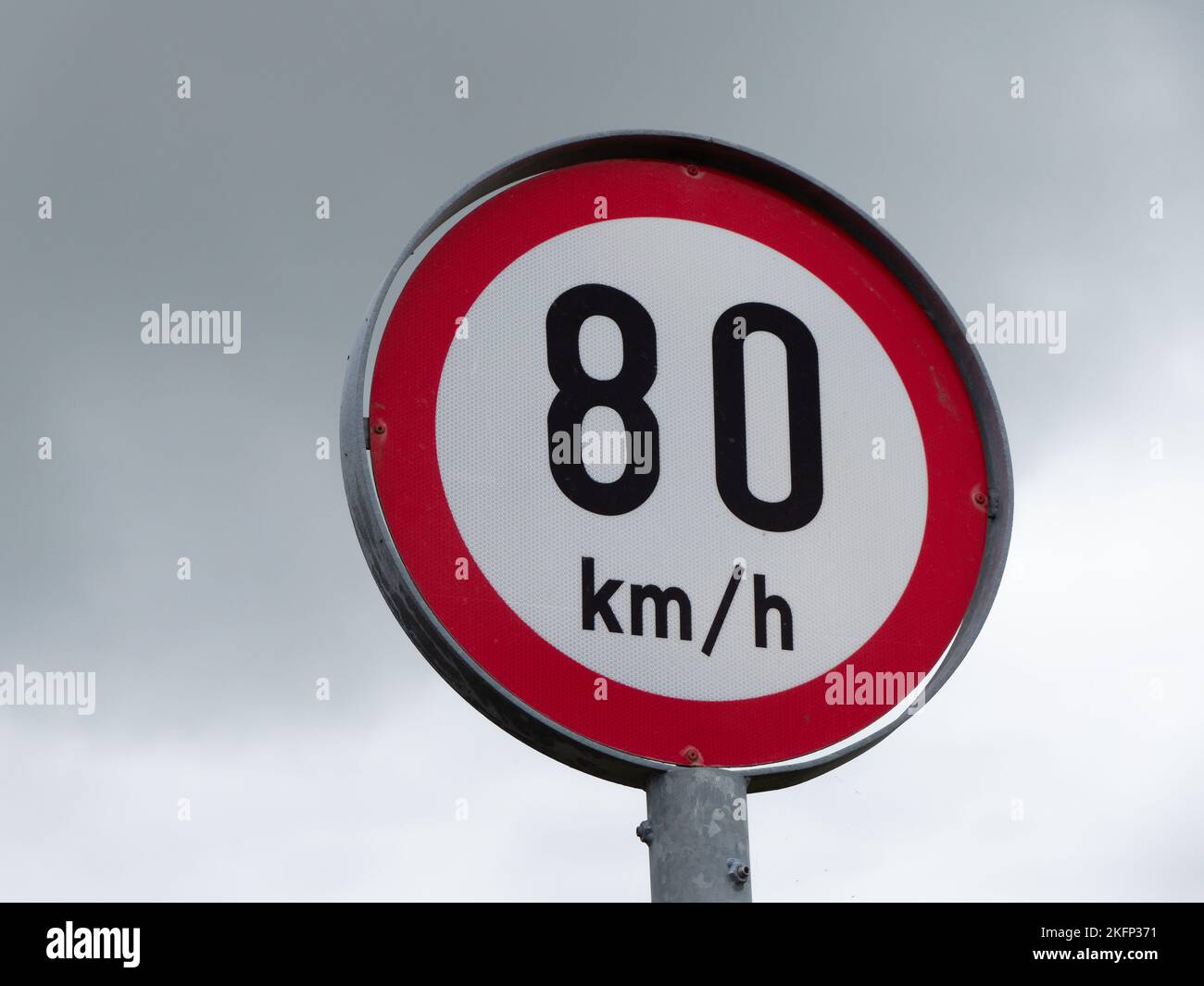 Round sign limiting speed on the background of a cloudy sky. Signs warning of a maximum speed of 80 km h Stock Photo