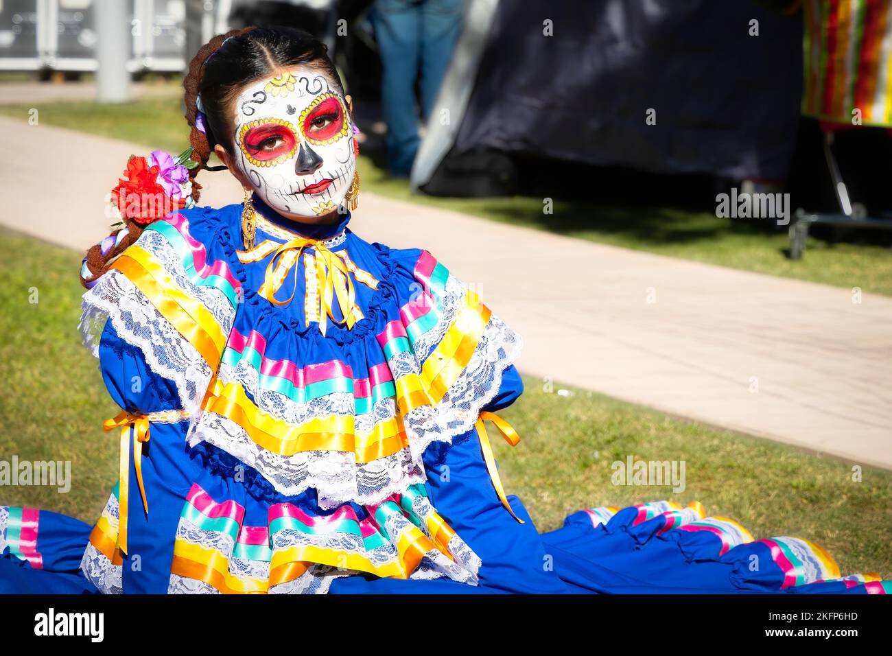 A woman sits on the ground at the 2022 Day of the Dead Festival and Parade in downtown El Paso, Texas. Stock Photo