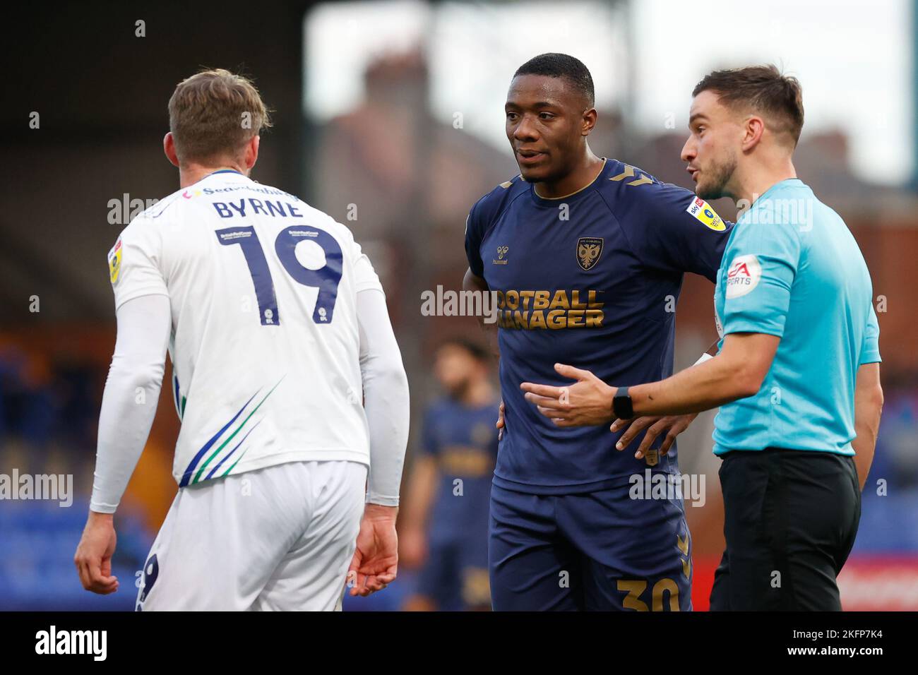 Referee Thomas Kirk talks to Paul Kalambayi #30 of AFC Wimbledon and Neill Byrne #19 of Tranmere Rovers during the Sky Bet League 2 match Tranmere Rovers vs AFC Wimbledon at Prenton Park, Birkenhead, United Kingdom, 19th November 2022  (Photo by Phil Bryan/News Images) Stock Photo