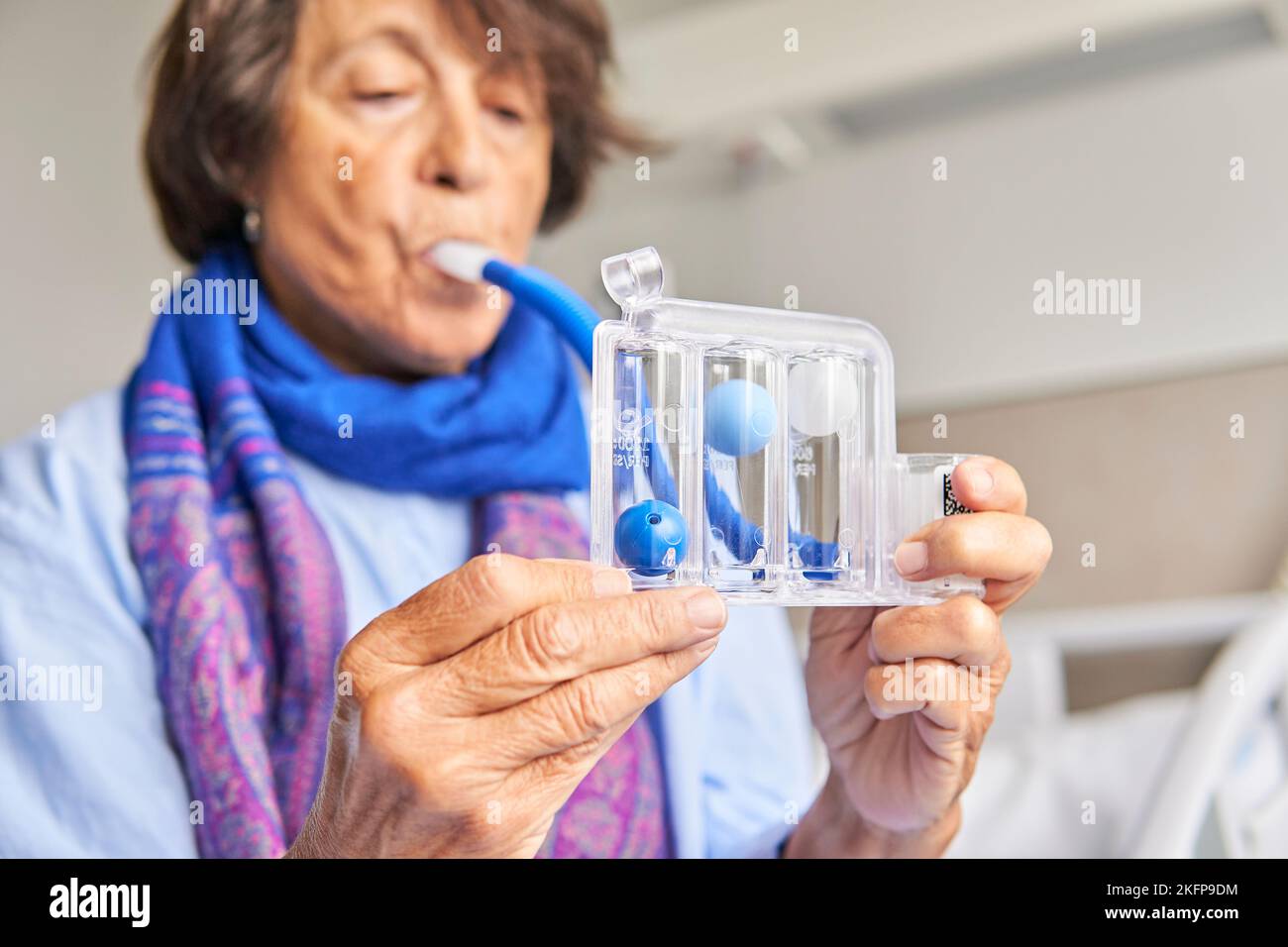 spirometer for breathing exercises. senior woman in hospital room