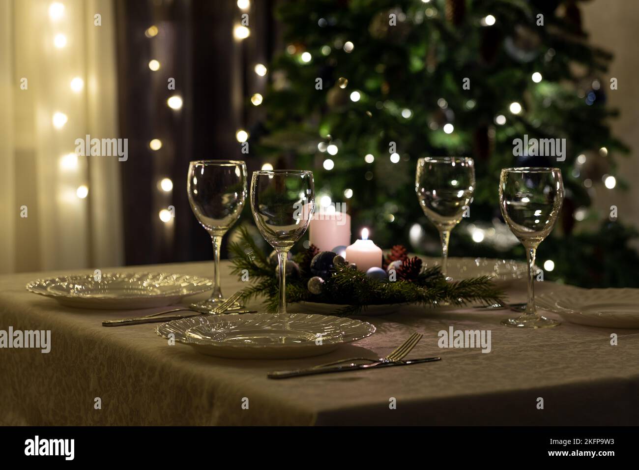 Serving the festive table. Food and drinks, plates and glasses. Evening lights and candles. Christmas dinner on Christmas Eve and New Year's Eve. Stock Photo