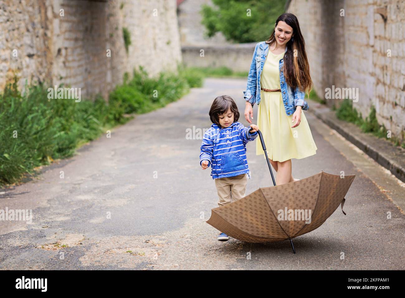 Mother and little baby boy playing with umbrella outdoor in old town Stock Photo