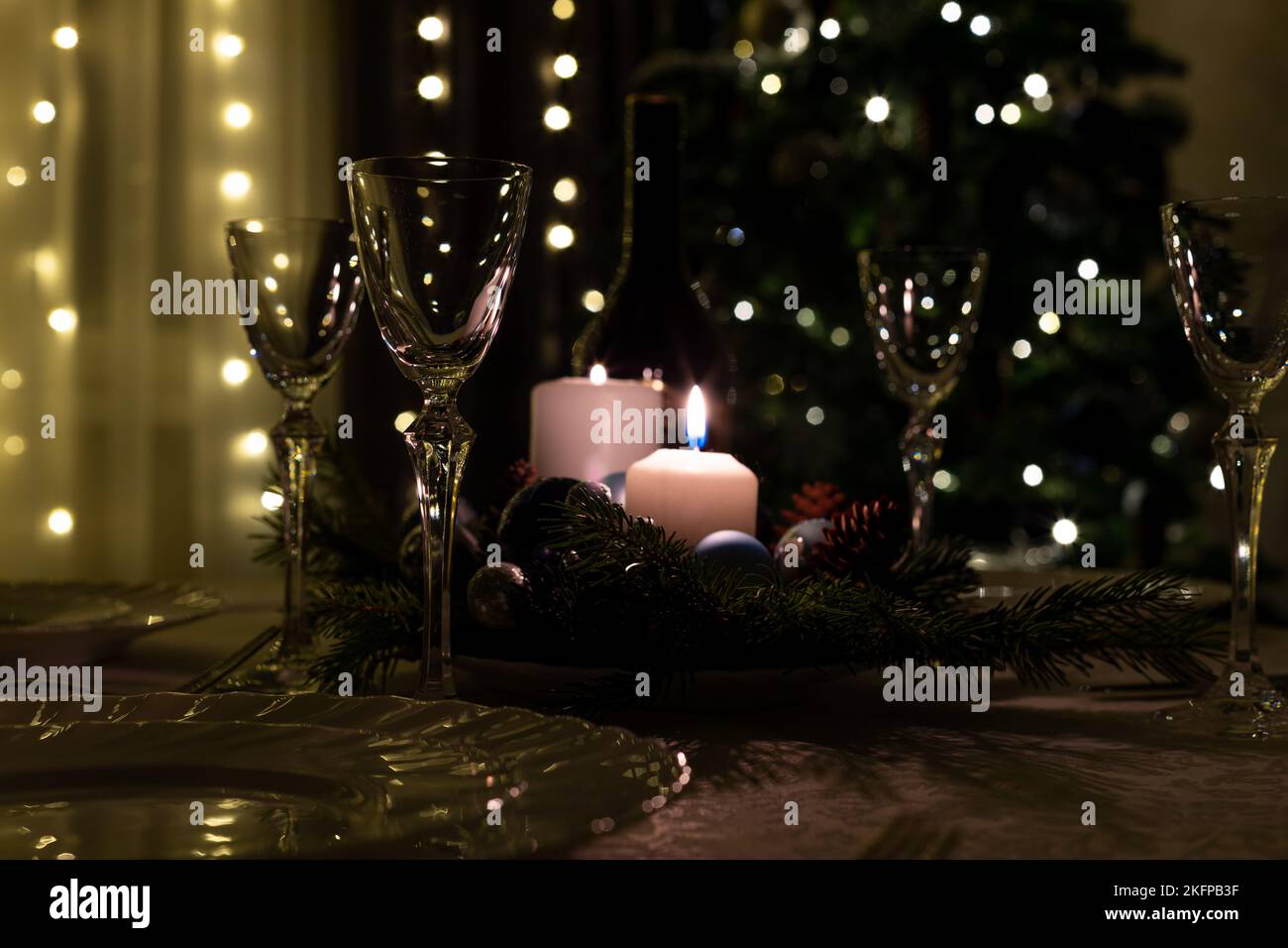 Serving the festive table. Food and drinks, plates and glasses. Evening lights and candles. Christmas dinner on Christmas Eve and New Year's Eve. Stock Photo