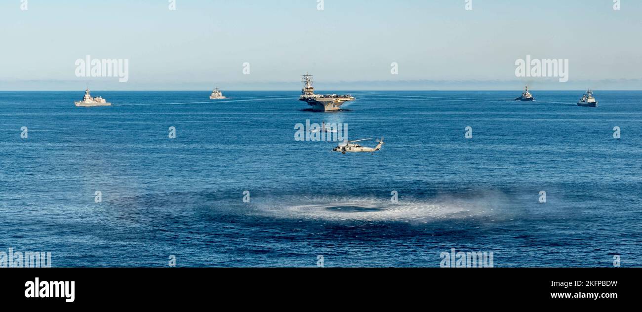 220930-N-DW158-1180 WATERS EAST OF THE KOREAN PENINSULA (Sept. 30, 2022) An MH-60S Sea Hawk attached to the Golden Falcons of Helicopter Sea Combat Squadron (HSC) 12, hovers in front of the U.S. Navy’s only forward-deployed aircraft carrier, USS Ronald Reagan (CVN 76), a U.S. Navy Los Angeles-class fast-attack submarine, Ticonderoga-class guided-missile cruiser USS Chancellorsville (CG 62), Arleigh Burke-class guided-missile destroyer USS Benfold (DDG 65), Republic of Korea (ROK) Navy destroyer ROKS Munmu the Great (DDH 976) and Japan Maritime Self-Defense Force (JMSDF) destroyer JS Asahi (DD Stock Photo