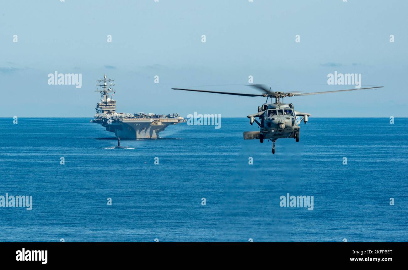 220930-N-DW158-1338 WATERS EAST OF THE KOREAN PENINSULA (Sept. 30, 2022) An MH-60S Sea Hawk attached to the Golden Falcons of Helicopter Sea Combat Squadron (HSC) 12, hovers in front of the U.S. Navy’s only forward-deployed aircraft carrier, USS Ronald Reagan (CVN 76), a U.S. Navy Los Angeles-class fast-attack submarine, Ticonderoga-class guided-missile cruiser USS Chancellorsville (CG 62), Arleigh Burke-class guided-missile destroyer USS Benfold (DDG 65), Republic of Korea (ROK) Navy destroyer ROKS Munmu the Great (DDH 976) and Japan Maritime Self-Defense Force (JMSDF) destroyer JS Asahi (DD Stock Photo