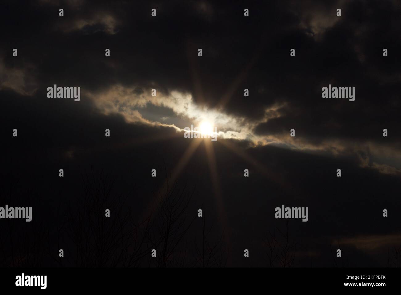 A view of the sun shining through dark clouds Stock Photo - Alamy