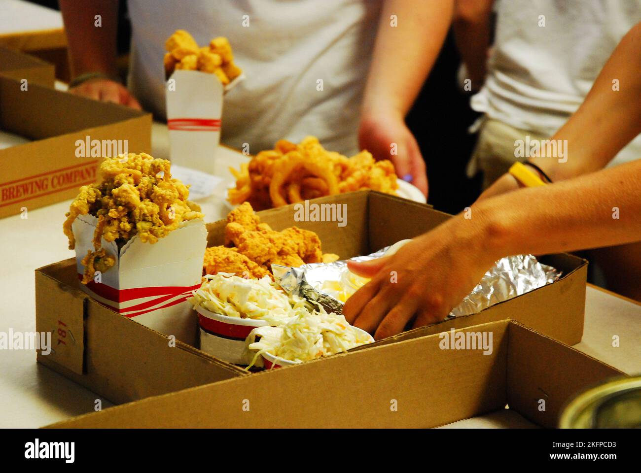 Workers' hands move quickly to prepare and pack a take out order at a busy and fast paced seafood restaurant Stock Photo