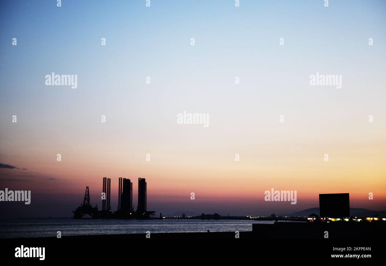 Silhouette of bridge connected offshore oil production platforms at oil field during sunset Stock Photo