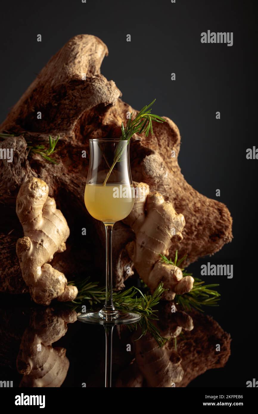 Ginger liquor with a rosemary branch on a black background with an old snag Stock Photo Alamy