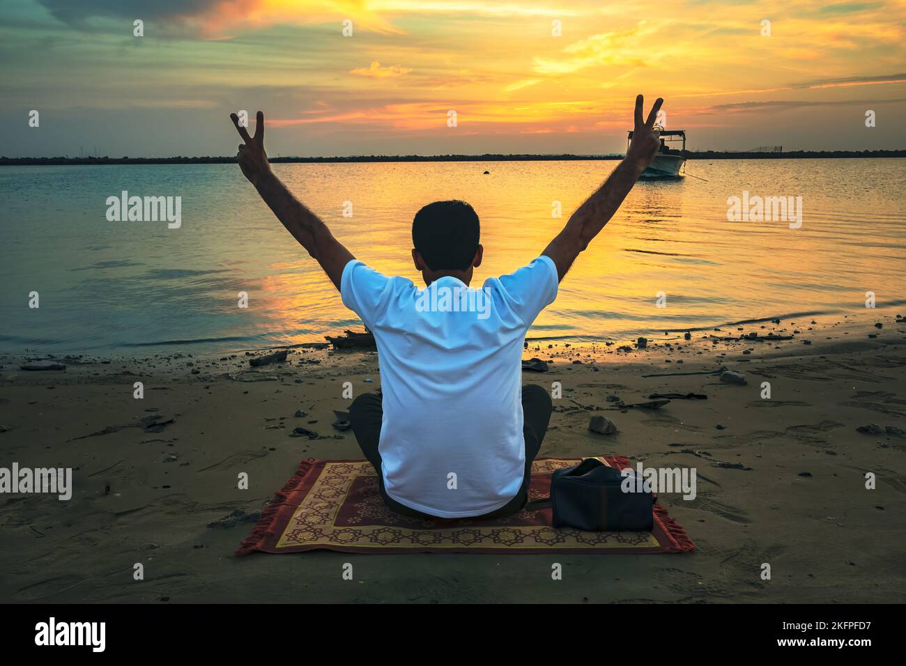 Man sitting and watching sunset over the sea. Dammam, Saudi Arabia ...
