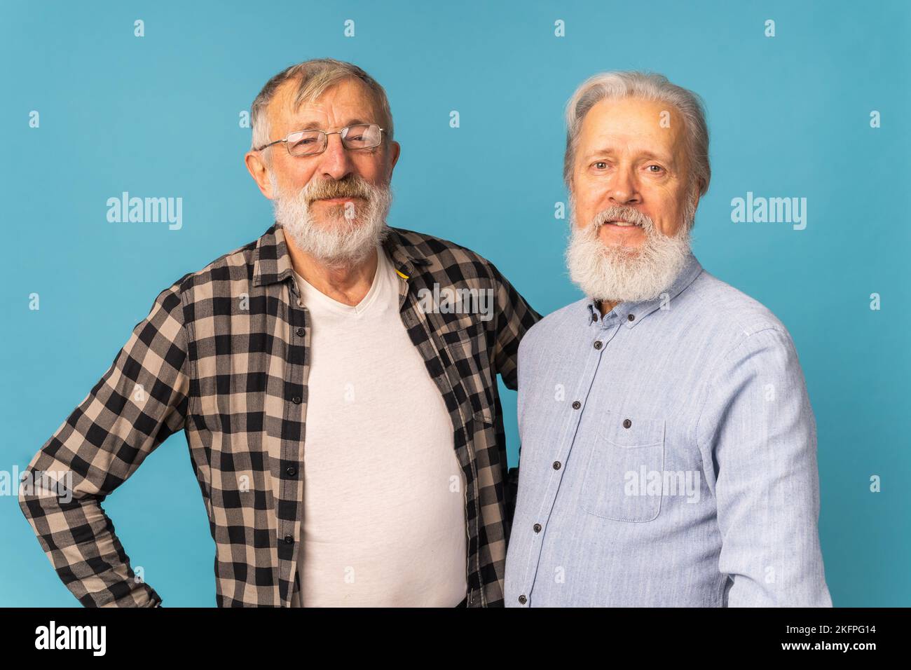 Portrait two elderly man friends standing over blue background - friendship, aged and senior people Stock Photo