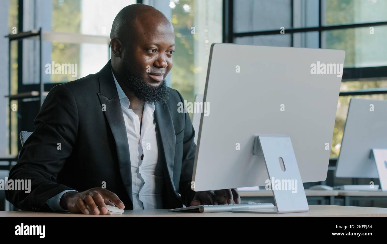 African american businessman commercial agent expert site in modern office work on computer develop website coding program search data online Stock Photo