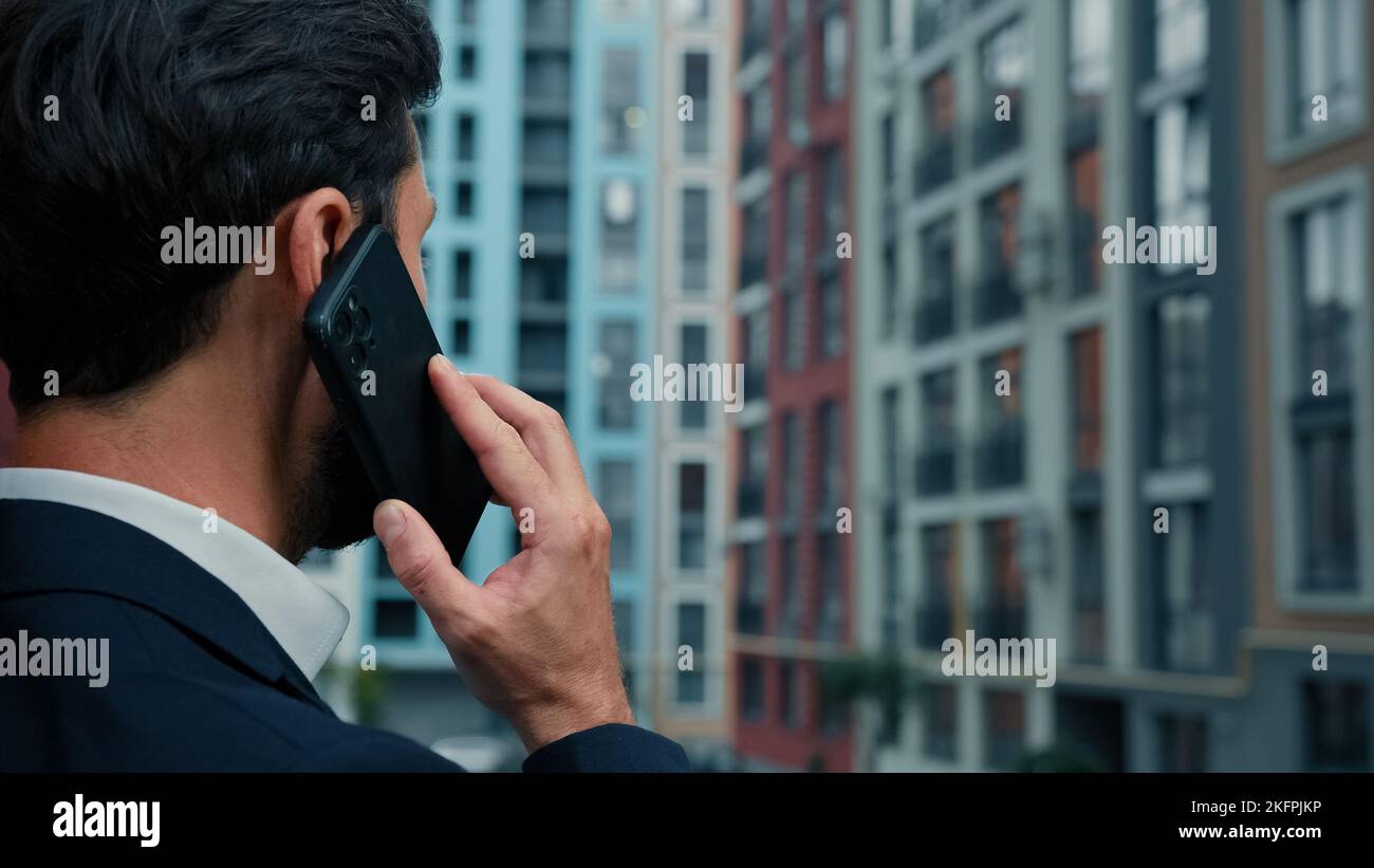 Rear back view businessman talk mobile phone outside on city street use
