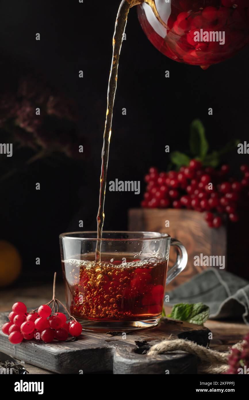 Viburnum tea is poured into a cup from a glass teapot, pouring process ...