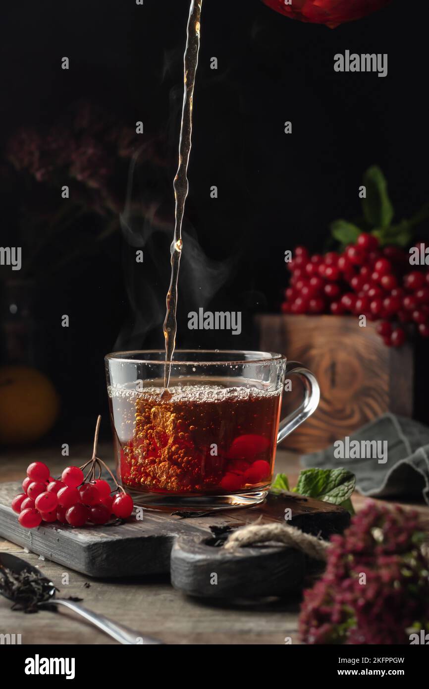 Viburnum tea is poured into a cup with steam, pouring process. Autumn ...