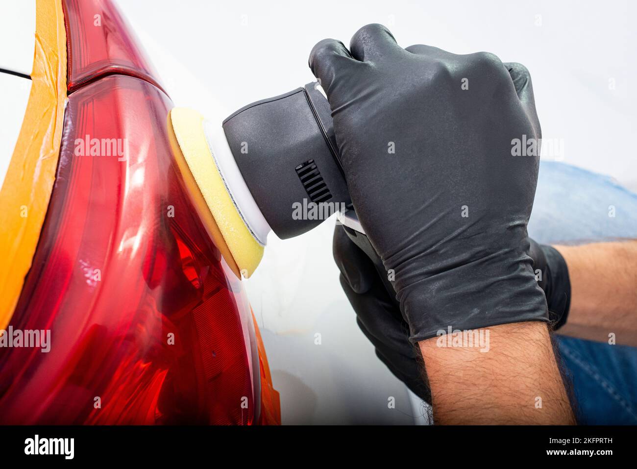 Car polish wax worker hands applying protective tape before polishing