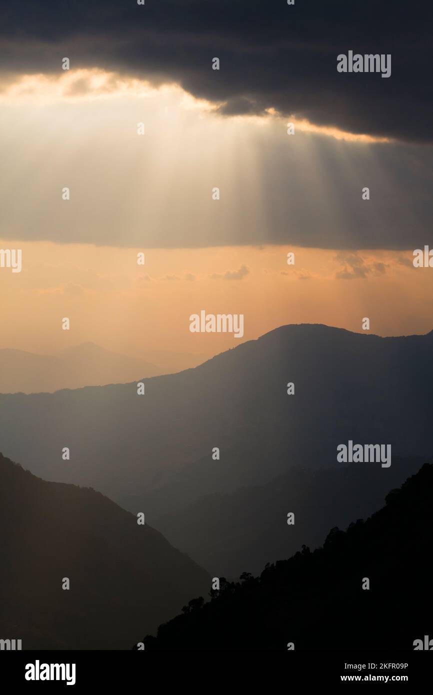 Sun beams over silhouetted Himalayan foothills, south of Annapurna Range. Nepal. Stock Photo