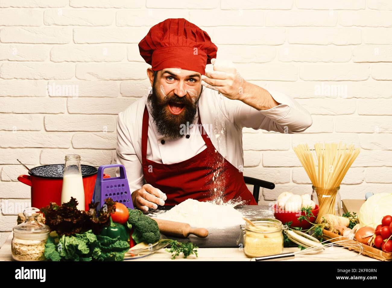 Chef makes dough. Man with beard plays with flour Stock Photo