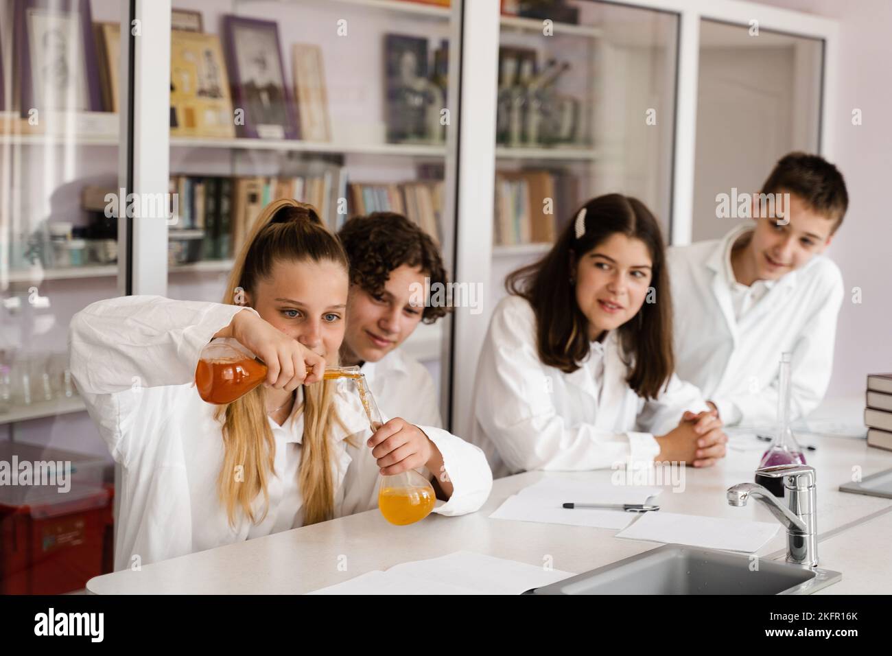 Chemistry lesson. Schoolgirl and classmates holds flask for experiments ...
